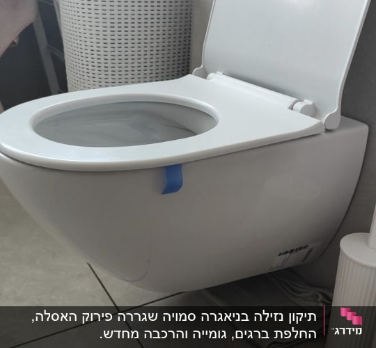 אסלה תלויה בחדר אמבטיה עם מגבות וסל כביסה
